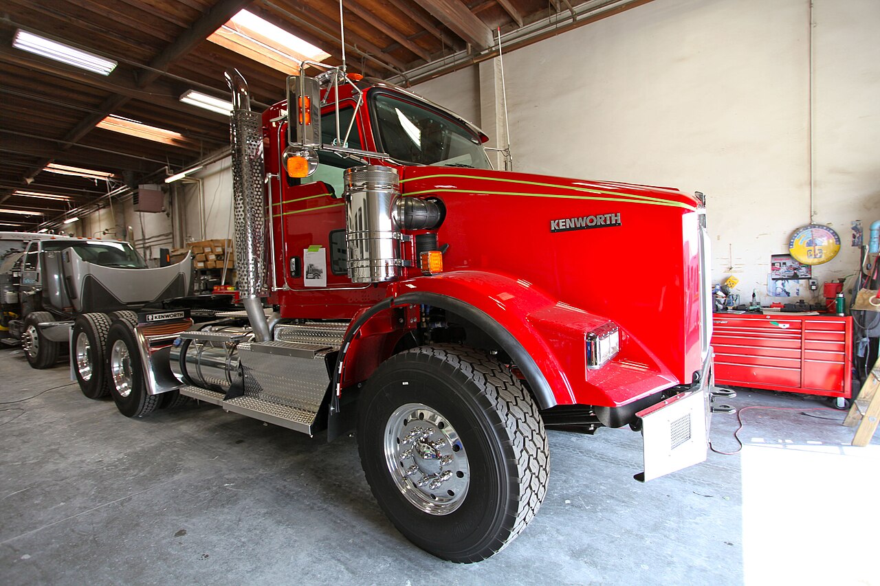 A red Kenworth truck inside a repair workshop